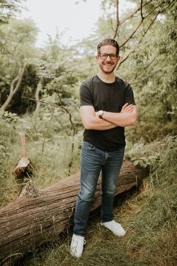 a moderately attractive male, smiling with his arms folded